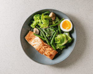 Tigela com ovos, salmão, nozes e verduras representando alimentos para unhas saudáveis em São Paulo.